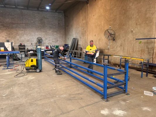 Two Tulla fabricators assembling large blue structural steel frames